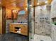 Bathroom with dual sink vanity, tiled shower with glass enclosure, wood and stone accents at 6066 Crawford Gulch Rd, Golden, CO 80403