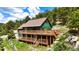 Green two-story home with a brown roof and a spacious wooden deck overlooking a green landscape at 6066 Crawford Gulch Rd, Golden, CO 80403