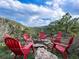 Outdoor seating area with red Adirondack chairs arranged around a stone fire pit with scenic views at 6066 Crawford Gulch Rd, Golden, CO 80403