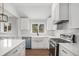 A well-lit kitchen boasts white cabinets, stainless steel appliances, and a farmhouse sink under a window at 1990 Ulster St, Denver, CO 80220