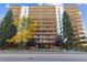 Low angle exterior of a high-rise condo building with red brick, large balconies, and beautiful trees at 4570 E Yale Ave # 706, Denver, CO 80222