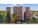 Exterior shot of a high-rise condo building with red brick and large balconies surrounded by mature trees at 4570 E Yale Ave # 706, Denver, CO 80222