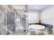 Bathroom featuring a soaking tub and glass shower with marble tile at 6260 Rain Dance Trl, Littleton, CO 80125