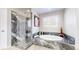 Bathroom featuring a marble-tiled shower, luxurious soaking tub, and a window for natural light at 6260 Rain Dance Trl, Littleton, CO 80125