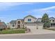 Charming home with brick accents, a three-car garage, an arched window, and lush landscaping at 15887 W Ellsworth Ln, Golden, CO 80401