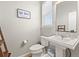 Stylish half bath with a modern pedestal sink, toilet, window and decorative wall art at 1527 Biffle Ct, Berthoud, CO 80513