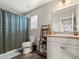 Well-lit bathroom featuring a shower with curtain, toilet, sink, and storage at 1527 Biffle Ct, Berthoud, CO 80513