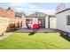 Beautifully landscaped backyard with artificial grass and modern deck with red Adirondack chairs at 945 Jackson St, Denver, CO 80206
