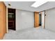 Bedroom with light gray carpeting and paneled walls, with closet and access to another room at 460 S Taft St, Lakewood, CO 80228