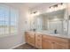 Bathroom featuring double sinks, granite countertops, wood cabinets and a large mirror at 10610 Reunion Pkwy, Commerce City, CO 80022