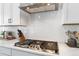 Modern kitchen features stainless gas cooktop, white tile backsplash, and sleek countertops at 1581 Diamond Hill Ct, Castle Rock, CO 80104