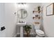 Stylish powder room featuring a pedestal sink, round mirror, and decorative shelves with plants at 1581 Diamond Hill Ct, Castle Rock, CO 80104