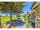 Landscaped front yard with a mature tree, stone pathway, and green lawn adjacent to the home's entrance at 23738 E Clifton Pl, Aurora, CO 80016