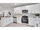 Modern kitchen with white cabinets, stainless steel appliances, sleek countertops, and breakfast bar seating at 8801 E 16 Ave, Denver, CO 80220