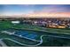 Picturesque aerial view of a community with tennis courts and a pond at dusk, perfect for recreation and relaxation at 19688 E 52Nd Ave, Denver, CO 80249