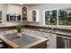 Bright kitchen featuring white cabinets, tile floor, an island with seating, and views of the natural landscape at 2571 Sw Grapevine Rd, Idledale, CO 80453