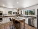 Bright kitchen featuring white cabinets, tile floor, an island with seating, and views of the natural landscape at 2571 Sw Grapevine Rd, Idledale, CO 80453