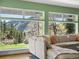 Bright living room with scenic mountain views visible through large windows surrounding the comfortable sectional sofa at 2571 Sw Grapevine Rd, Idledale, CO 80453
