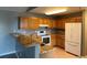 Well-lit kitchen with breakfast bar, oak cabinets, granite counters, and white appliances at 12304 W Cross Dr # 304, Littleton, CO 80127