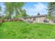 A large backyard featuring green grass, a patio with a table, and a wood fence, providing ample outdoor space at 6147 Jellison Way, Arvada, CO 80004