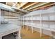 Unfinished basement features built-in shelving and a workbench, offering versatile space for storage and projects at 6147 Jellison Way, Arvada, CO 80004