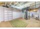 Unfinished basement featuring white shelving, green accent rug, and exposed ductwork providing ample storage and utility space at 6147 Jellison Way, Arvada, CO 80004