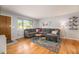Cozy living room featuring hardwood floors, a gray sectional, and a large window at 6147 Jellison Way, Arvada, CO 80004