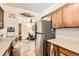 A well-lit kitchen with a stainless steel refrigerator and wood cabinets next to a dining area at 125 S Fulton Ave, Fort Lupton, CO 80621