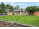 Charming single-story home featuring a covered porch, well-maintained lawn, and a rustic wooden retaining wall at 1865 S Knox Ct, Denver, CO 80219