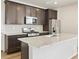 Modern kitchen with dark cabinets, stainless steel appliances, a center island, and wood-look flooring at 6504 N Malaya St, Aurora, CO 80019