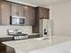Modern kitchen boasts stainless steel appliances, dark cabinets, and a large center island with sink and faucet at 6504 N Malaya St, Aurora, CO 80019