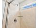 Close up of tiled shower with glass shelf and shower head with a view of blue skies through the window at 6504 N Malaya St, Aurora, CO 80019
