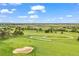 Aerial view of a lush green golf course with golfers playing and a sand trap at 7717 S Grape Ct, Centennial, CO 80122