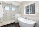 Bright bathroom featuring a glass shower, a soaking tub, and white tile walls at 6643 Barnstead Dr, Castle Pines, CO 80108