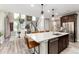 Bright kitchen featuring stainless steel appliances, dark cabinets, a large island with seating, and pendant lights at 6643 Barnstead Dr, Castle Pines, CO 80108