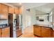 Well-lit kitchen featuring hardwood flooring, stainless steel refrigerator, and a partial view of the living room at 20431 E Union Cir, Aurora, CO 80015