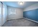 A simple bedroom with a blue accent wall, carpet flooring, window, and closet at 3918 S Rome Ct, Aurora, CO 80018