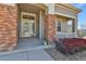 Inviting front porch featuring brick columns, a glass door and well-manicured landscaping at 1034 Halfmoon Dr, Castle Rock, CO 80104