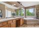 Luxurious main bathroom featuring double vanity, makeup area, large window, and a soaking tub at 14682 W Amherst Pl, Lakewood, CO 80228