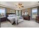Spacious main bedroom with a tray ceiling, ceiling fan, a large bed and dresser, and serene natural light at 14682 W Amherst Pl, Lakewood, CO 80228