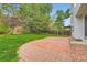 Backyard featuring a brick patio, green grass, a wood fence, mature trees, and a garden at 1842 Reliance Cir, Superior, CO 80027