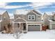 Charming two-story home with a gray garage, a cozy porch, and snow-covered landscape at 381 Rainbow Ln, Lafayette, CO 80026
