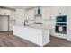 Kitchen features white cabinets, a long island, and stainless steel appliances at 9237 Truckee Ct, Commerce City, CO 80022