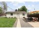 The backyard features a green lawn, patio with furniture and an umbrella, and a neutral building that offers additional space at 3039 W Denver Pl, Denver, CO 80211