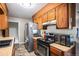 Galley kitchen features wood cabinetry, stainless steel refrigerator and black stove at 547 S 3Rd Avenue, Brighton, CO 80601