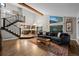 Open-concept living room with hardwood floors, stone fireplace and staircase to a second story loft at 15220 E Caley Ave, Centennial, CO 80016