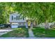 Charming home with gray siding, dark shutters, yellow door, attached garage, and mature trees in a well-manicured yard at 8710 Alta Vista Dr, Arvada, CO 80004