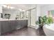 This modern bathroom has a dual sink vanity, a glass-enclosed shower, and a free-standing tub at 21451 E 60Th Ave, Aurora, CO 80019