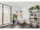 Bright bathroom featuring a modern tub, glass-enclosed shower, and a decorative plant stand at 21451 E 60Th Ave, Aurora, CO 80019