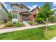 Inviting two-story home with a covered front porch, complemented by a lush green lawn and mature landscaping at 21451 E 60Th Ave, Aurora, CO 80019